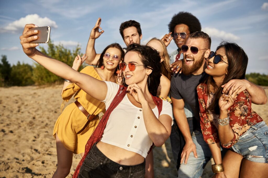 Grupo de amigos tirando selfie na praia durante viagem de feriado com o Clube Bancorbrás