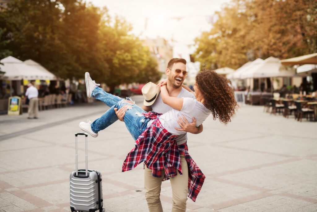 Casal sorrindo e se abraçando em viagem romântica pelas ruas de uma cidade com o Clube Bancorbrás.