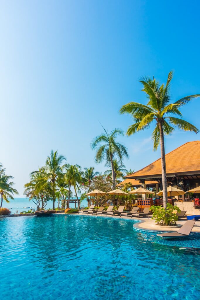 Piscina de resort tropical cercada por coqueiros, representando o conforto de um clube de férias.