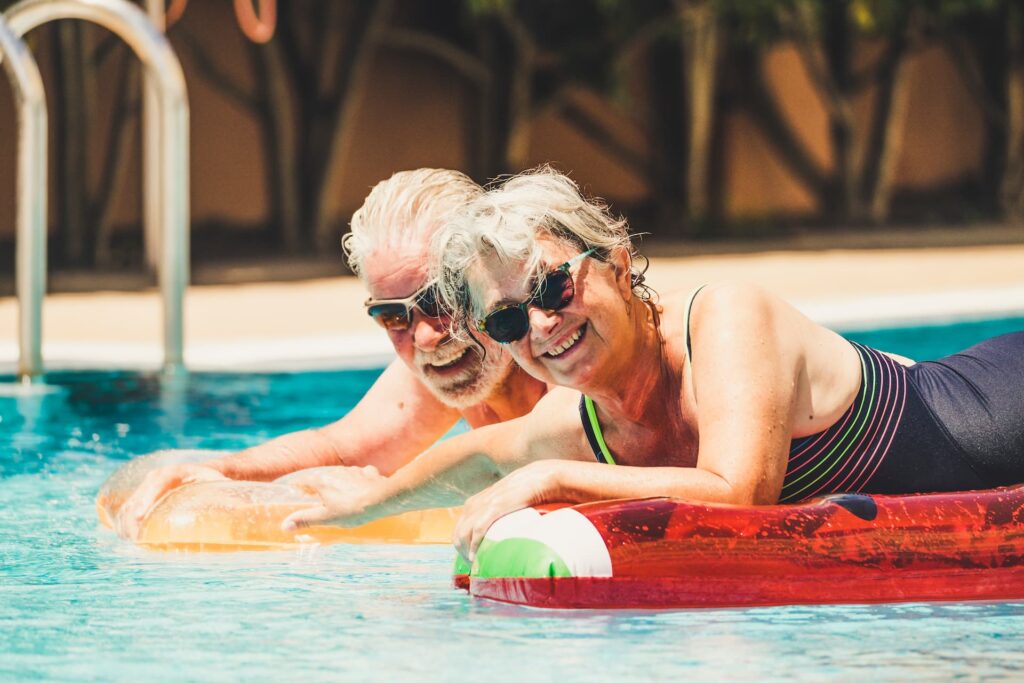 Casal sênior sorridente aproveitando a piscina durante as férias com o Clube Bancorbrás.