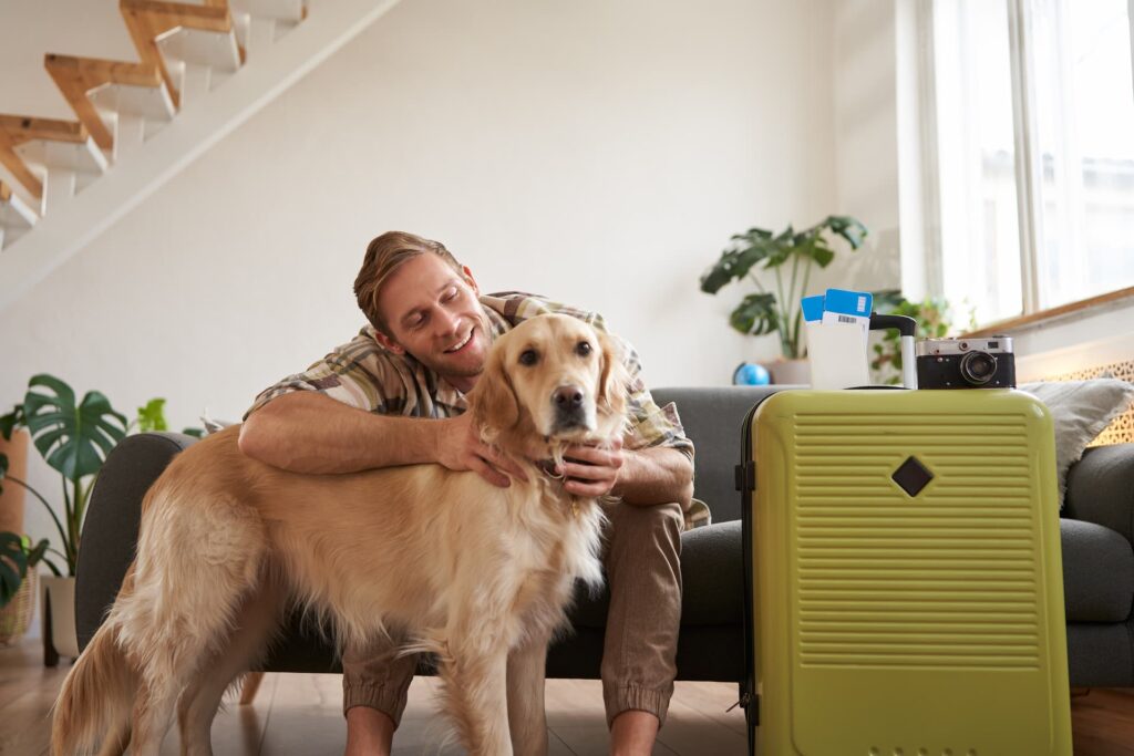 Homem pronto para viajar com seu cachorro e mala feita, representando os preparativos para férias em um hotel pet-friendly.