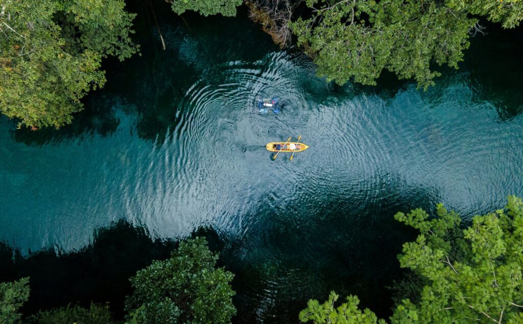 Pessoas remando em caiaques de acrílico sobre um lago de águas termais no Hot Park