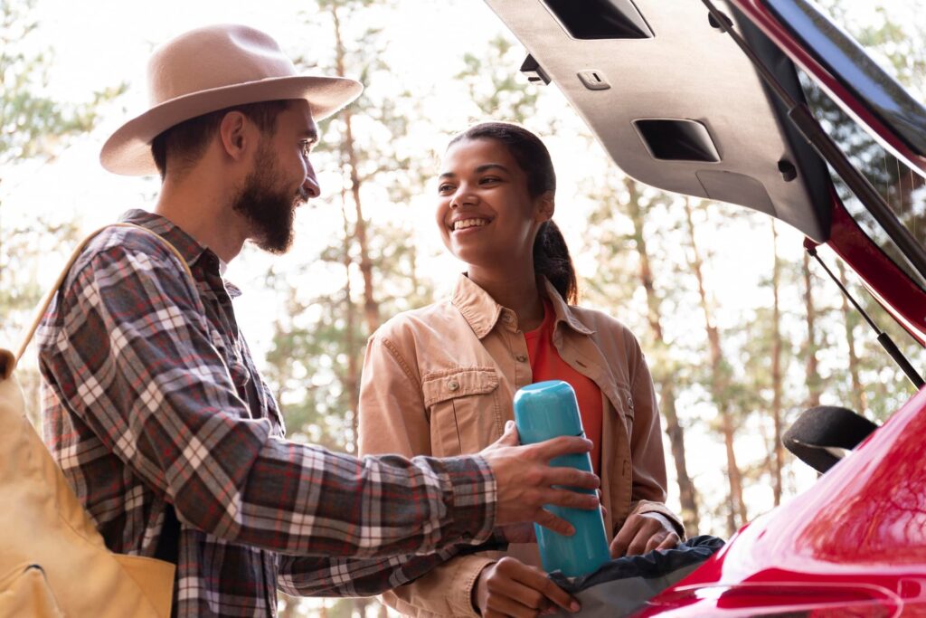 Casal se preparando para uma viagem, revisando o carro antes de pegar estrada no Rio de Janeiro.