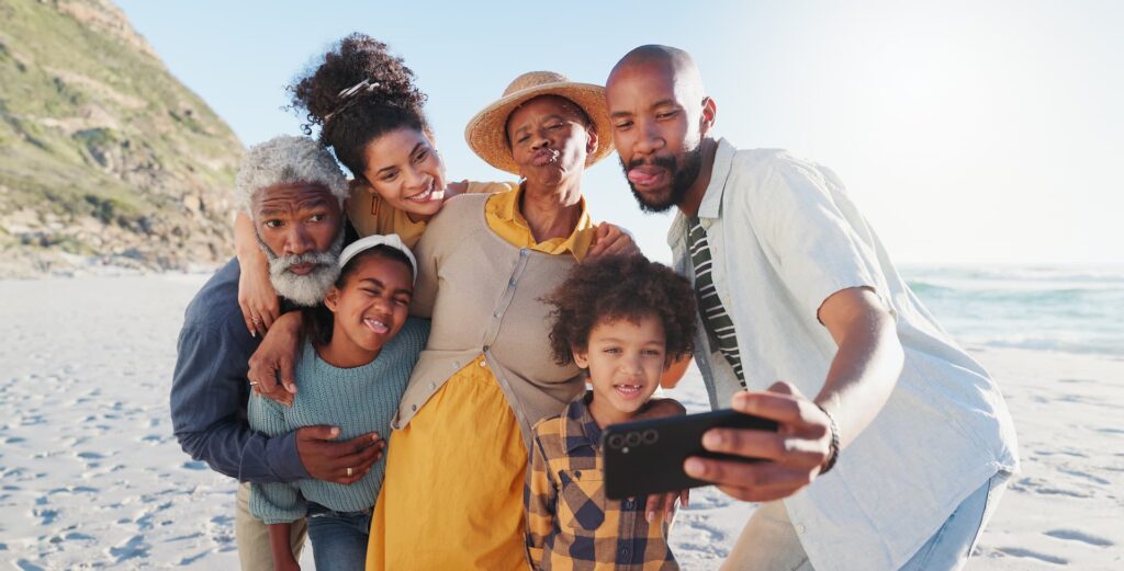 Família tirando selfie na praia durante férias em família, viagem com crianças e momentos inesquecíveis.