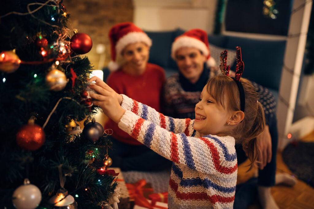 menina decorando árvore de Natal em casa durante viagem de fim de ano