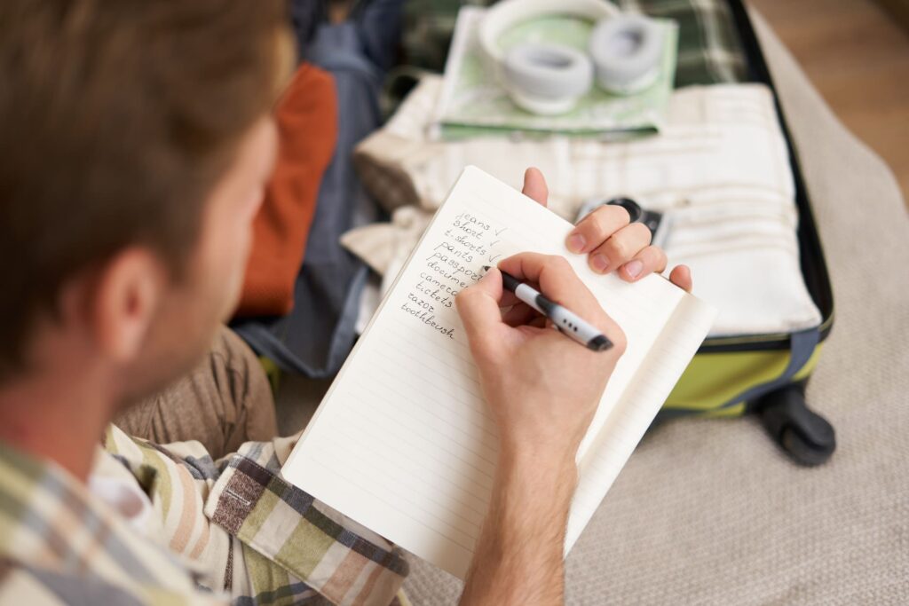 Homem organizando mala e fazendo anotações para viagem internacional