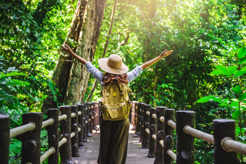 Pessoa em meio à floresta com os braços levantados, em contato com a natureza
