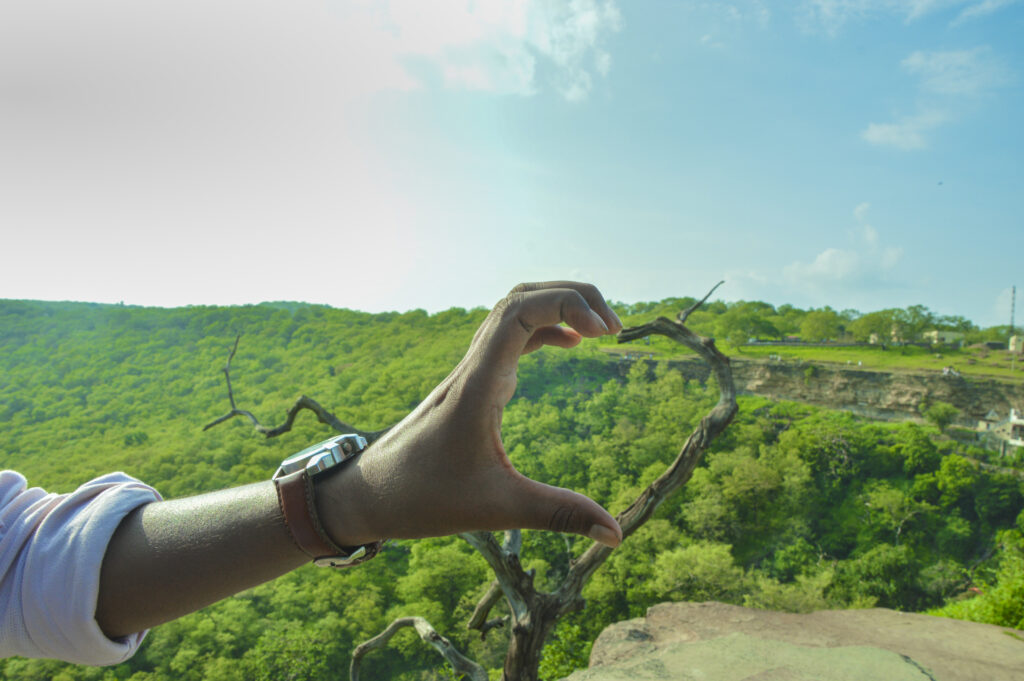 Mão de criança formando meio coração, simbolizando cuidado com o meio ambiente