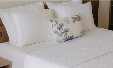 Quarto de hotel moderno com cama de casal ampla, enxoval branco e iluminação suave no Nord Easy Camboinha.