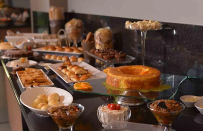 Buffet de café da manhã farto com frutas, pães e bolos dispostos em um restaurante de hotel em Palmas.